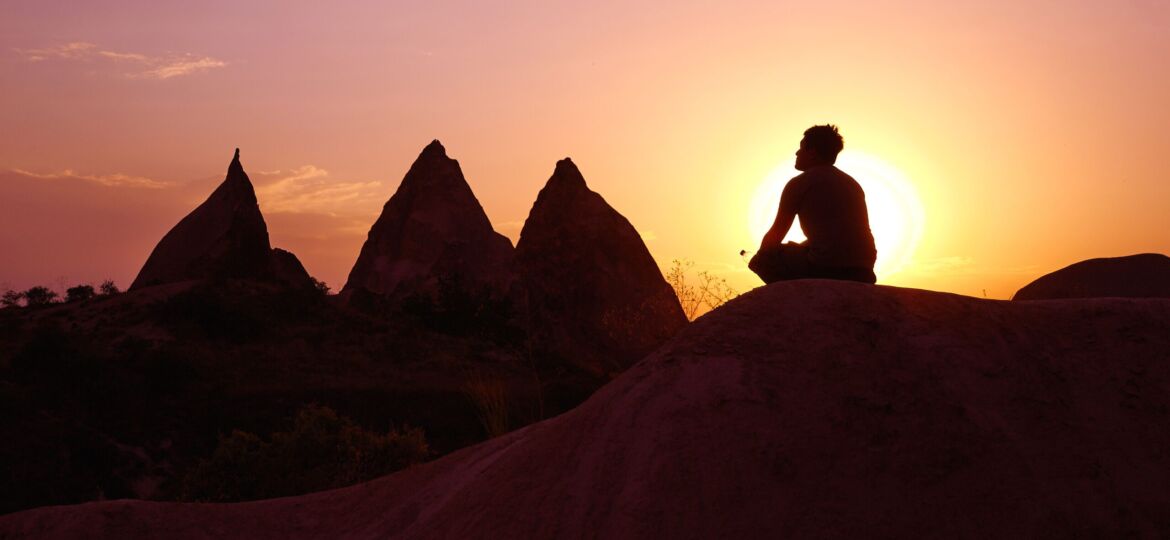Man meditating with sun silhouette