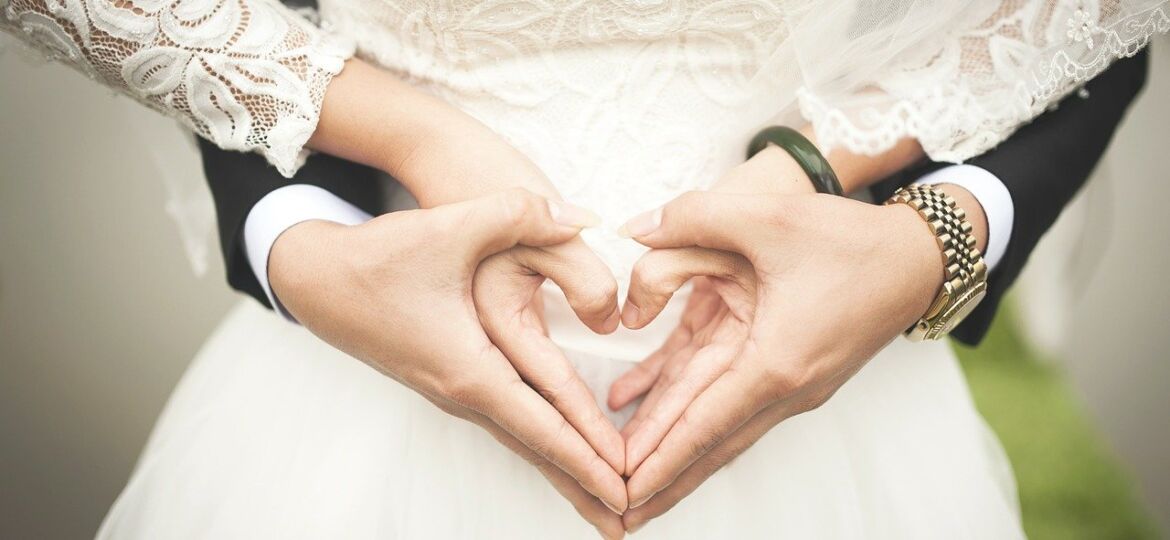 Bride and groom making the shape of a heart with their hands