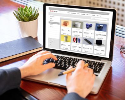 Online shop website developer working with a laptop, office desk background.