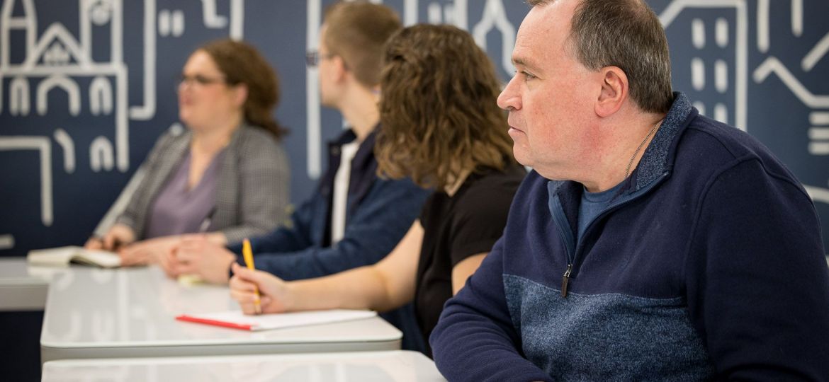 TRG team seated at a conference table listening attentively during a meeting